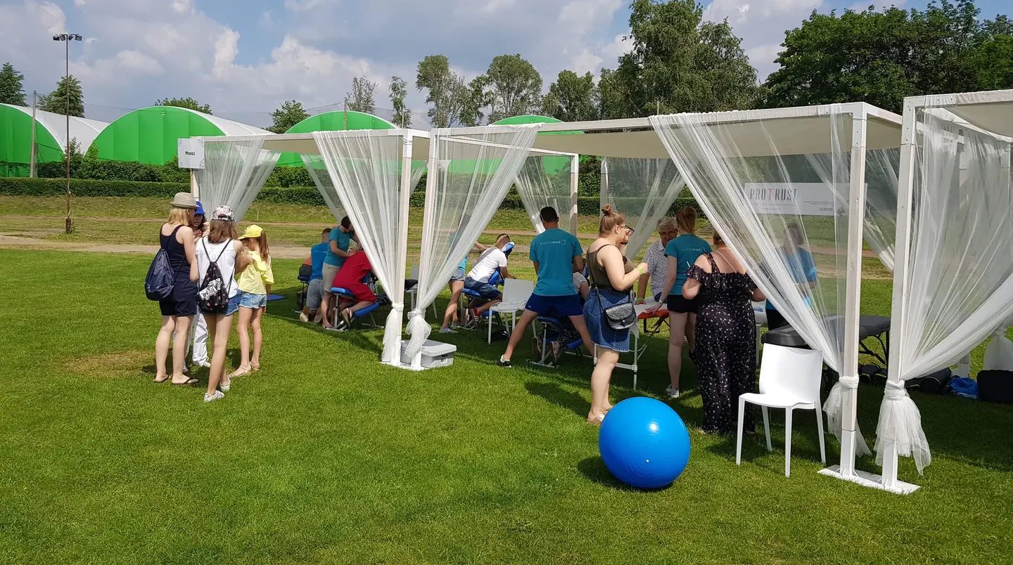 Strefy zdrowia w namiotach podczas pikniku firmowego, pracownicy na piłkach i przy stanowiskach