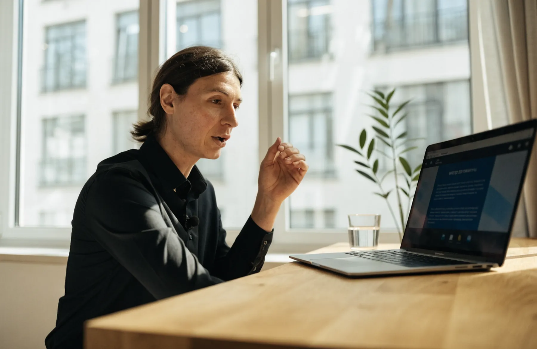 Prowadzący mówi do laptopa podczas webinaru, w tle duże okno